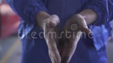 一位不知名的汽车修理工在维修站修车后展示了他脏兮兮的双手。闭合。